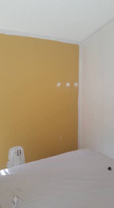 Room wall in the process of being painted a bright yellow